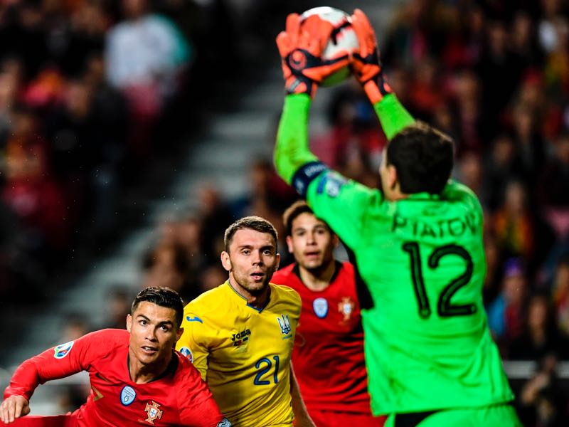 Ukraine's goalkeeper Andriy Pyatov (R) stops a shot on goal by Portugal's forward Cristiano Ronaldo (L) during the Euro 2020 group B qualifying football match between Portugal and Ukraine at the Luz stadium in Lisbon on March 22, 2019. (Photo by PATRICIA DE MELO MOREIRA / AFP)
